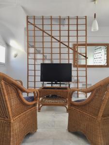 a living room with two wicker chairs and a television at Luminous house 100m from the sea in Nea Roda