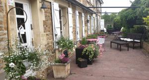 an outdoor patio with flowers and tables and chairs at La Ferme De Saint Julien in Charleville-Mézières