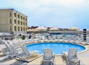 a group of lounge chairs and a swimming pool at Hotelux La Playa Alamein in El Alamein