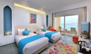 a hotel room with two beds and a television at Hotelux La Playa Alamein in El Alamein