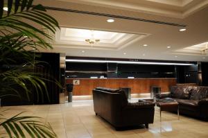 eine Lobby mit zwei Ledersesseln und einem Klavier in der Unterkunft Oita Regal Hotel in Ōita