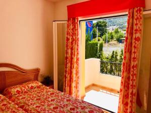 sypialnia z łóżkiem i dużym oknem w obiekcie Casa de familia w mieście Calpe