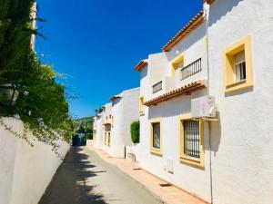 alejka pomiędzy dwoma białymi budynkami z niebieskim niebem w obiekcie Casa de familia w mieście Calpe