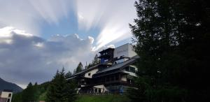 um edifício sobre uma colina com o sol no céu em Kinder- und Familienhotel Nockalm em Innerkrems