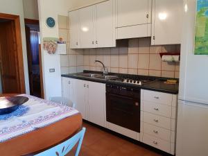 una cucina con armadi bianchi, lavandino e tavolo di Appartamento via Alghero a San Teodoro