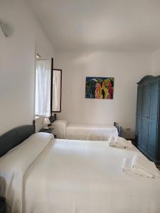 a white bedroom with two beds and a painting on the wall at La Via Del Mare in Arenella