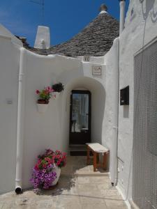 a white building with two potted plants and a bench at Trullo Delle Sorelle in Alberobello