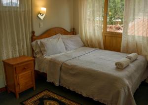 a bedroom with a bed with a wooden headboard and a window at Eco Lodge Los Perales-Urubamba in Urubamba