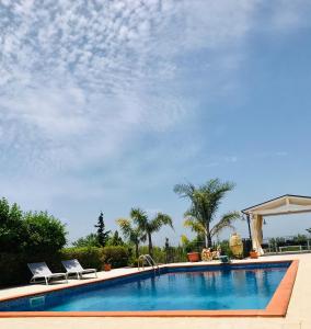 - une grande piscine avec 2 chaises et un parasol dans l'établissement Casa Vacanze Belvedere, à Partinico