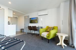 a living room with a green chair and a table at 239 on Lincoln Motel in Christchurch