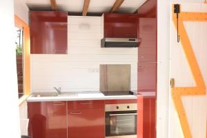 una piccola cucina con armadi rossi e piano cottura di padjembel a Lamentin
