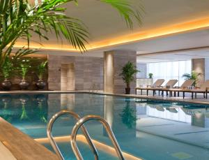 a swimming pool in a hotel with chairs and plants at Wanda Realm Beijing in Beijing