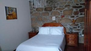a bedroom with a bed and a stone wall at Casa da Boa Vista em Viadal in Vale de Cambra