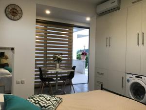 a bedroom with a table and a kitchen with a washing machine at Summer Studio - Zakynthos!! in Argassi