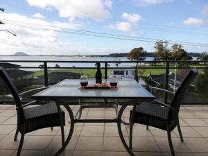 una mesa con 2 sillas y una botella de vino en el balcón en Harbour Views Omokoroa en Omokoroa Beach