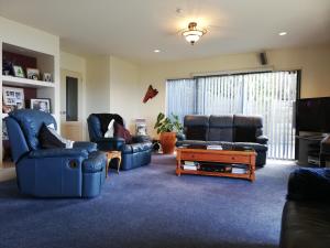 a living room with two chairs and a tv at Harbour Views Omokoroa in Omokoroa Beach