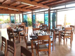 restauracja z drewnianymi stołami, krzesłami i oknami w obiekcie Hotel Enera w mieście Golem