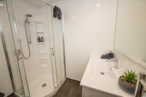 a white bathroom with a shower and a sink at Tasman Holiday Parks - Te Anau in Te Anau