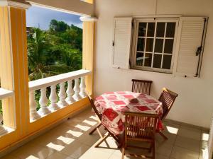balcón con mesa, sillas y ventana en Villa Josiane, en Sainte-Anne