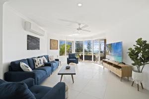una sala de estar con sofás azules y una mesa. en Kirra Palms Holiday Apartments, en Gold Coast