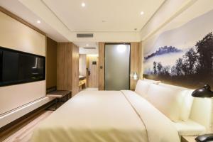 a hotel room with a bed and a flat screen tv at Atour Hotel Langfang Xichang Road in Langfang