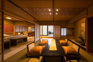 a room with a table and chairs and a bedroom at Tachibana Shikitei in Kaga
