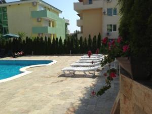 a row of white lounge chairs next to a swimming pool at Femili Hotel Diveda in Sveti Vlas
