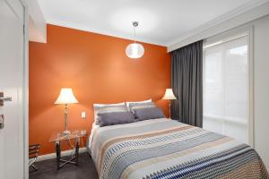 a bedroom with a bed with an orange wall at City Two Apartment in Mount Gambier
