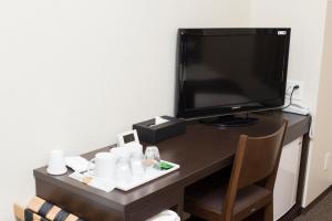 um quarto com uma secretária, uma televisão e uma cadeira em Lantana Osaka em Osaka