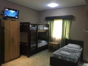 a bedroom with two bunk beds and a flat screen tv at Secter Place in Oslob