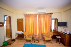 Zimmer mit Stühlen, einem Schreibtisch und einem TV in der Unterkunft Hotel Tara in Pokhara