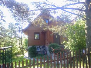 une maison en bois avec une clôture devant elle dans l'établissement Dom LECH Kaszuby do 8 os., à Olpuch