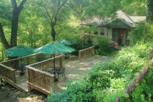 a deck with tables and umbrellas in front of a house at Hidden Springs Bed and Breakfast in Eureka Springs