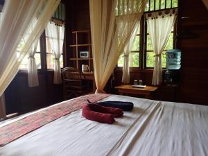 two pillows on a bed in a bedroom with windows at Two Fish Resort Lembeh in Bitung