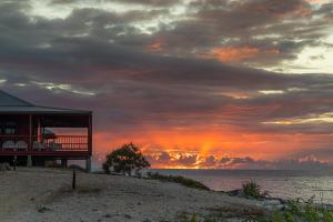 Guthalungra的住宿－Camp Island Lodge，海滩上的房子,背景是日落