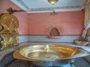 La salle de bains est pourvue d'une grande baignoire en or. dans l'établissement Riad & Spa Laurence Olivier, à Marrakech