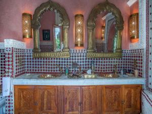 a bathroom with two sinks and two mirrors at Riad & Spa Laurence Olivier in Marrakesh