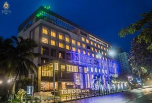 a building with a lit up facade at night at KPM TRIPENTA HOTEL in Kozhikode