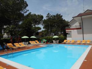 ein großer Pool mit Stühlen und Sonnenschirmen in der Unterkunft Casa Bianca Village Apartments in Lignano Sabbiadoro