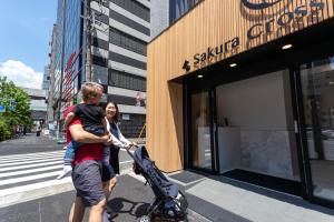 a woman holding a child in a stroller in front of a store at Sakura Cross Hotel Akihabara in Tokyo