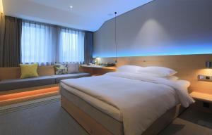 um quarto com uma cama grande e um sofá em EBO Hotel (Hangzhou West Lake) em Hangzhou
