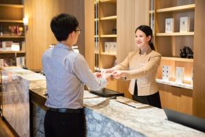 a man and a woman shaking hands at a counter at Hotel Kapok Shenzhen HouHai (Close to Shenzhen Bay) in Shenzhen