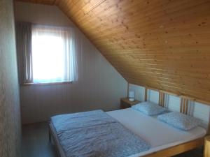 a bedroom with a bed with a wooden ceiling and a window at Domki letniskowe U Joli - Jolanta Potrykus in Władysławowo