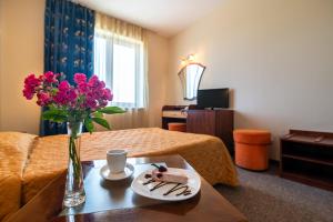 a room with a table with a plate of food and flowers at Adamo Hotel in Varna City