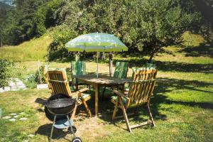 einen Tisch mit einem Sonnenschirm, Stühlen und einem Grill in der Unterkunft Riverside Apartment in Tarrenz