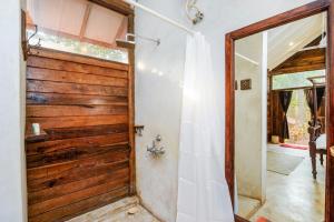 a bathroom with a wooden door and a mirror at Namaste Jungle - A Boutique Homestay in Assagao