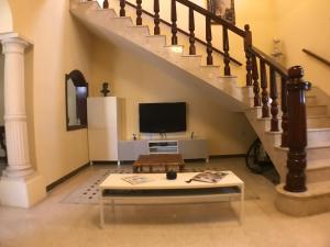 a living room with a staircase with a tv and a coffee table at Corner Townhouse 1Km from University in Msida