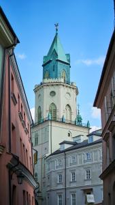 wysoki budynek z wieżą zegarową na górze w obiekcie Sztukmistrz Magician Art Rooms w mieście Lublin