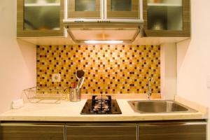 a kitchen with a sink and a stove top oven at Deluxe and Modern Studio M Gold Tower Apartment By Travelio in Bekasi +6 photos