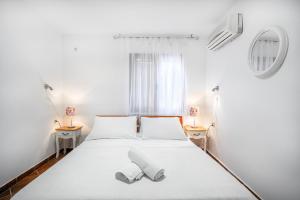a white bedroom with a bed with two shoes on it at Heritage Residence in Center with pool in Vodice +76 photos